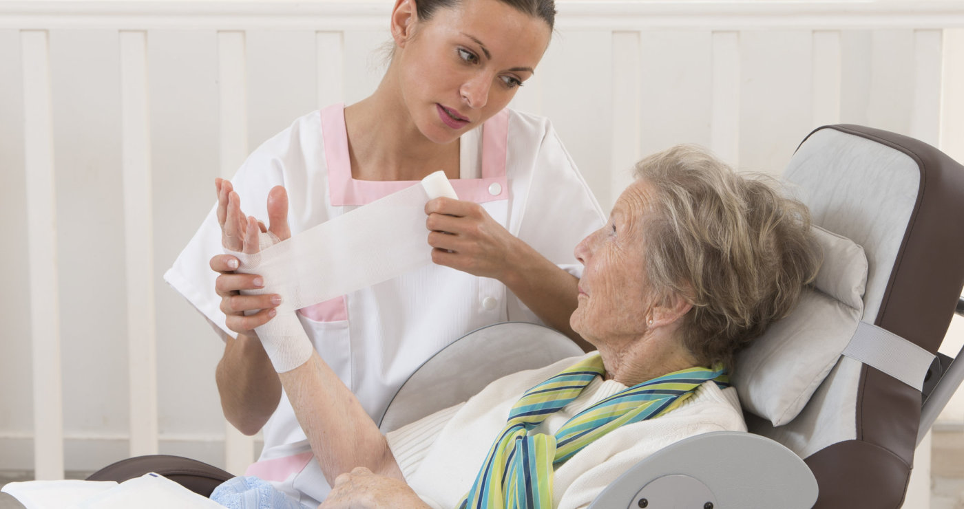 nurse treating the elderly woman's injury