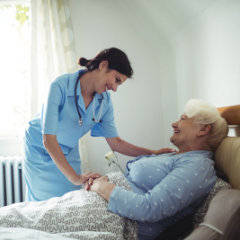 elderly lying in bed assisted by her aide