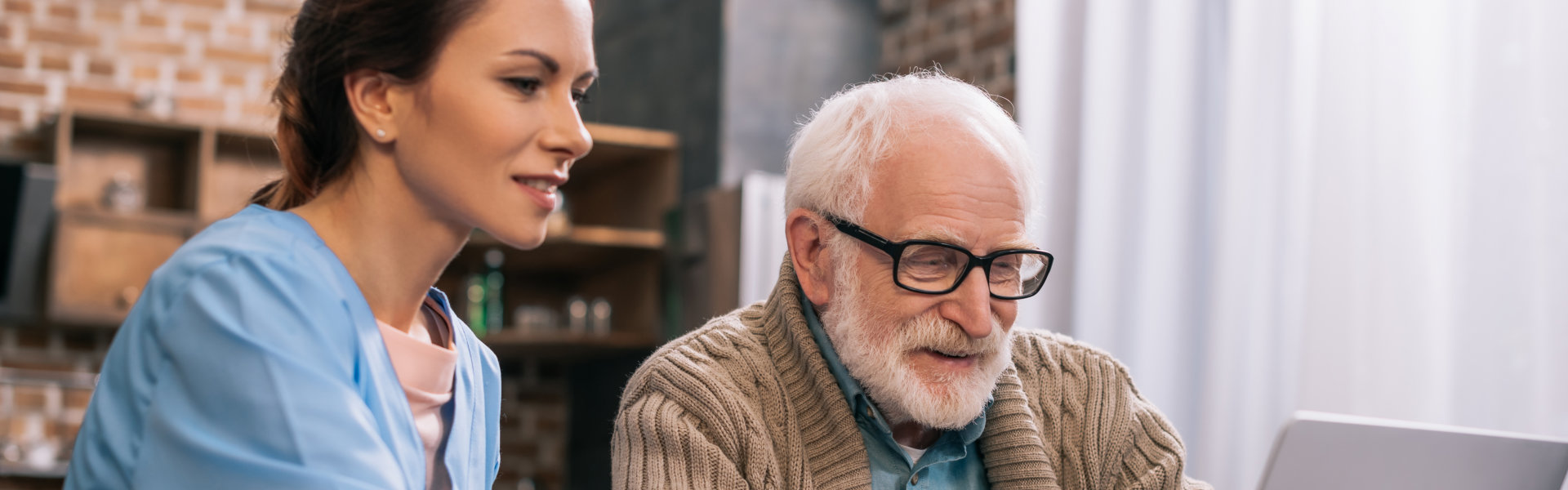 elderly and caregiver using laptop