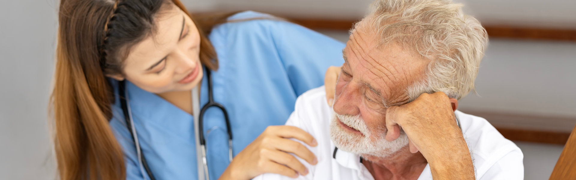 sad elderly comforted by her caregiver