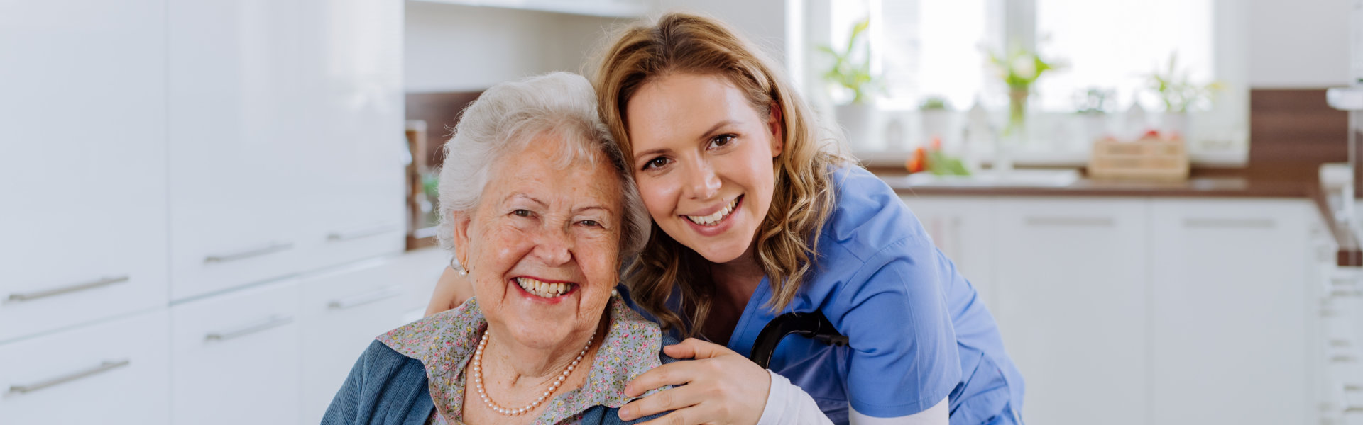 elderly woman smiling with her aide in a kitchen